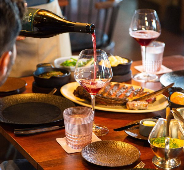 waiter pours red wine at mexican steakhouse in fairmont mayakoba