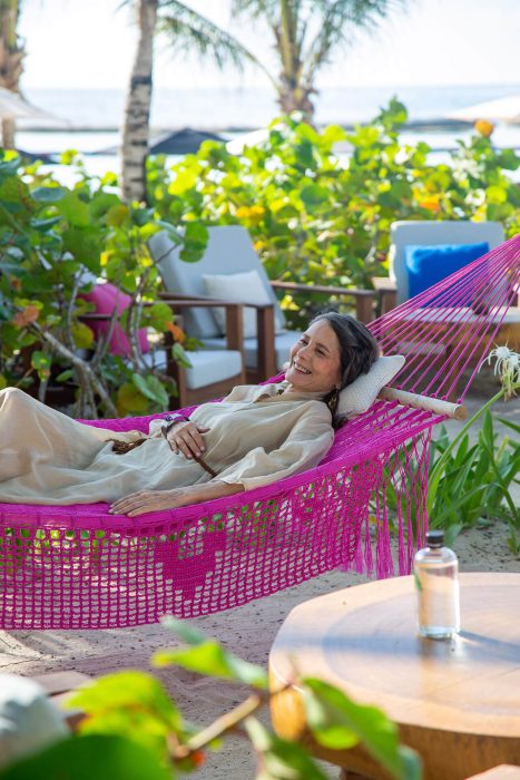 woman lounges on hammock at beach club under sandy shores