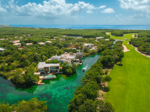 boat cruises through canals next to rainforest and golf course at mayakoba