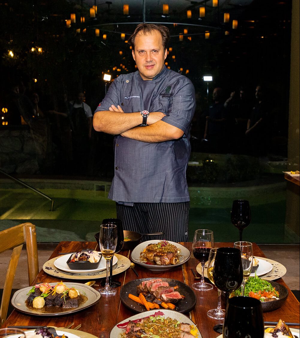 executive chef of banayan tree poses in front of dining table filled with meat foods