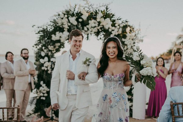 couple smiles as they walk down aisle at their wedding