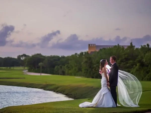 couple in wedding attire holds hands on golf course