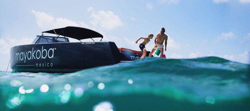 dad and son jump off mayakoba yacht into caribbean ocean