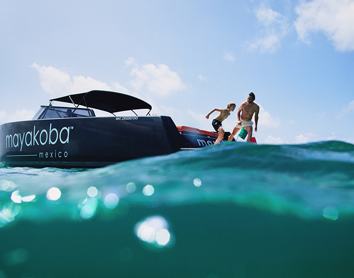 family dives into ocean water from mayakoba yacht