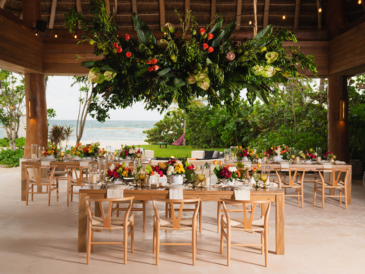 outdoor wedding table decorated under palapa with beach view
