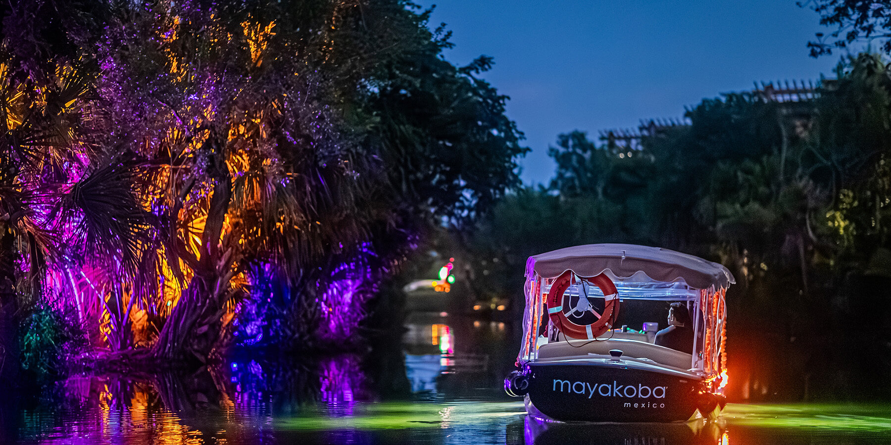 boat cruises through lit canal at mayakoba for holiday event