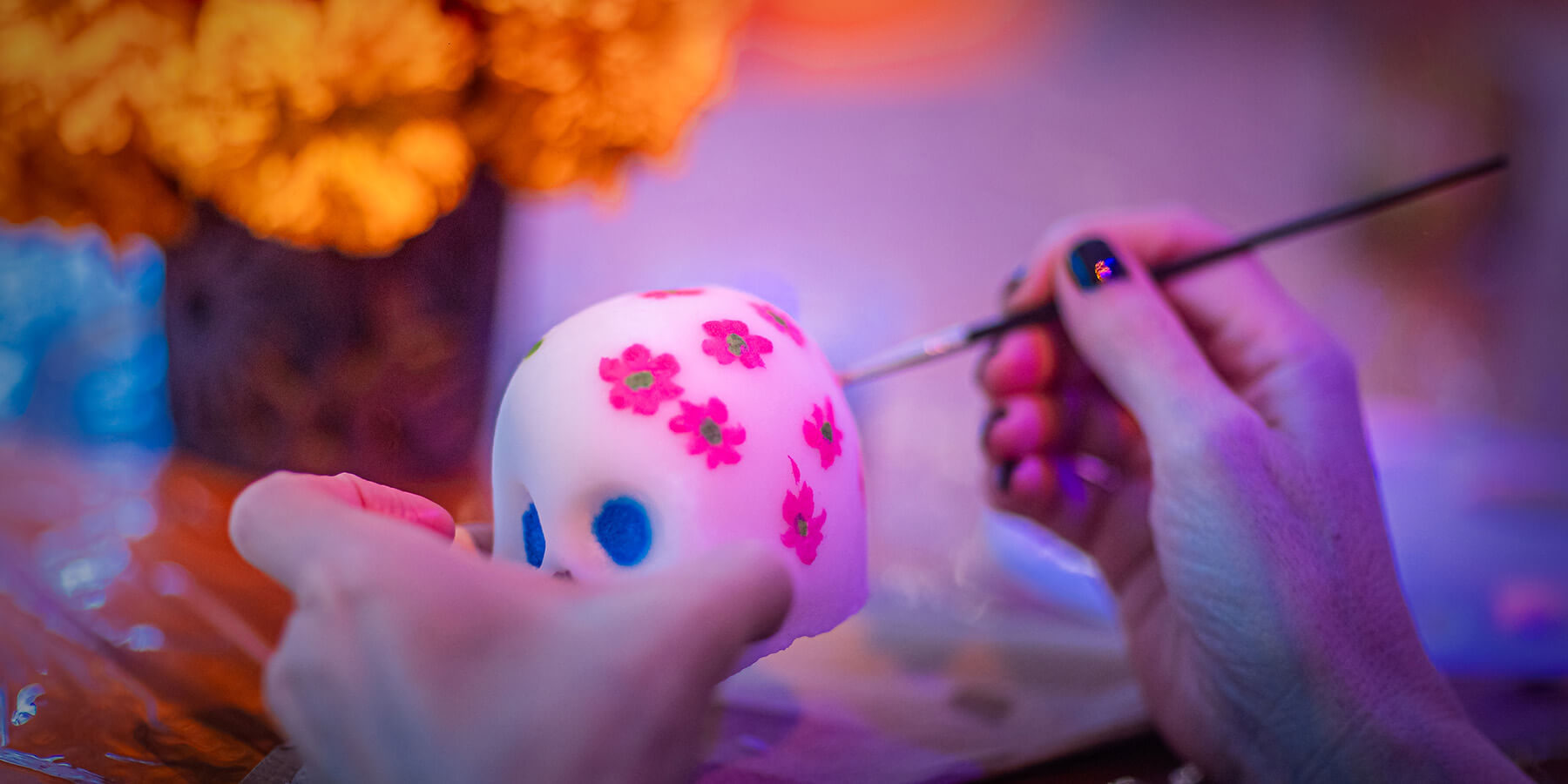 person paints skull at dia de muertos event at mayakoba