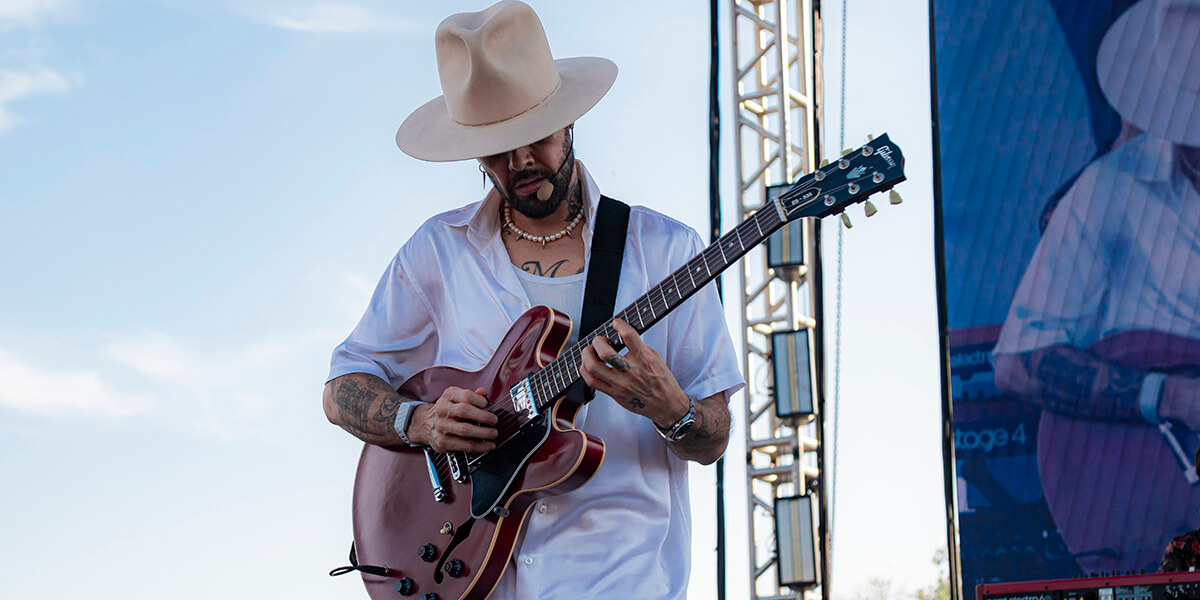 guitarist strums instrament on outdoor stage during mayakoba concert