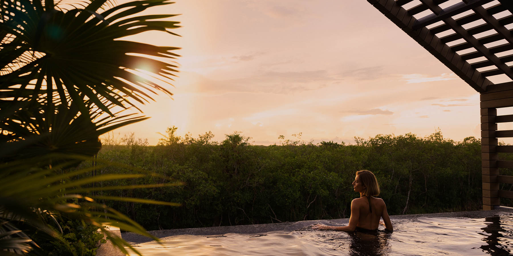 woman looks out from rooftop villa infinity pool at mayakoba