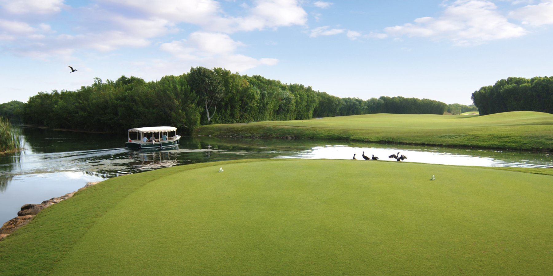 eco boat cruises canals next to green on mayakoba golf course